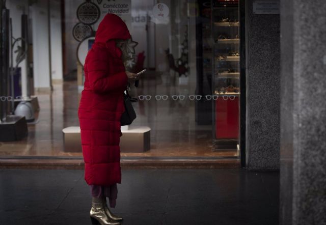 Una mujer bajo un soportal espera que cese la lluvia Una mujer bajo un soportal espera que cese la lluvia