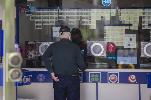 Una persona compra lotería en una administración Una persona compra lotería en una administración