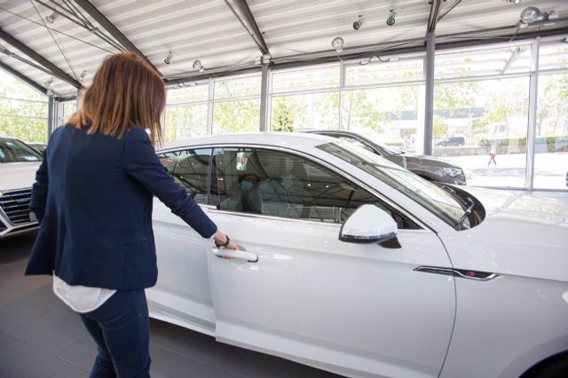 Una mujer abre un coche en un concesionario Una mujer abre un coche en un concesionario